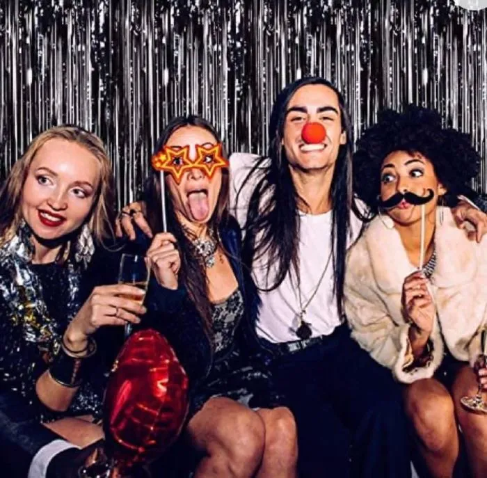 Party goers with fun photo booth props, like mustaches and wigs