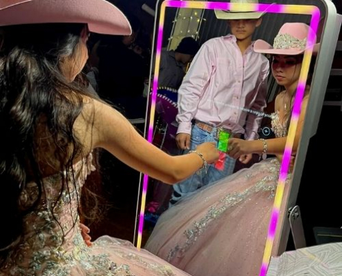 Girl in pink dress using mirror photo booth at event