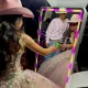 Girl in pink dress using mirror photo booth at event