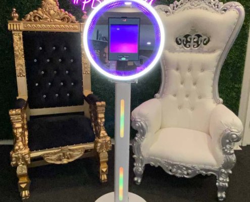 Photo booth in front of a decorative throne chair and a plush throne chair.