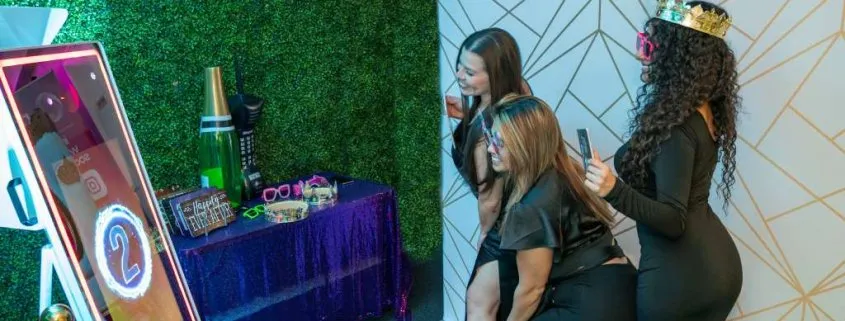 Three women at a party pose for a photo with a Miami photo booth.